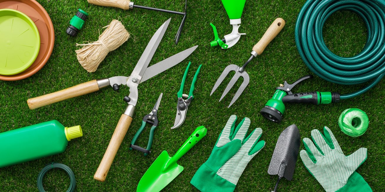 Gardening tools and utensils on a lush green meadow, top view, garden manteinance, landscaping and hobby concept
